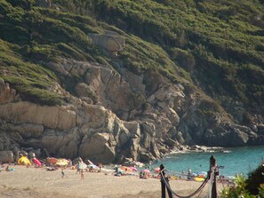 A beach with rocky cliffs, umbrellas, and people. - Tizzano, villa with individual garden. (Sartène)