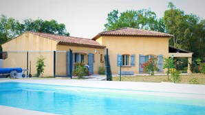 A swimming pool area with a house and a fenced yard. - Single storey villa, 4 bedrooms, swimming pool, near the beaches of the Gulf of Saint Trop (Grimaud)
