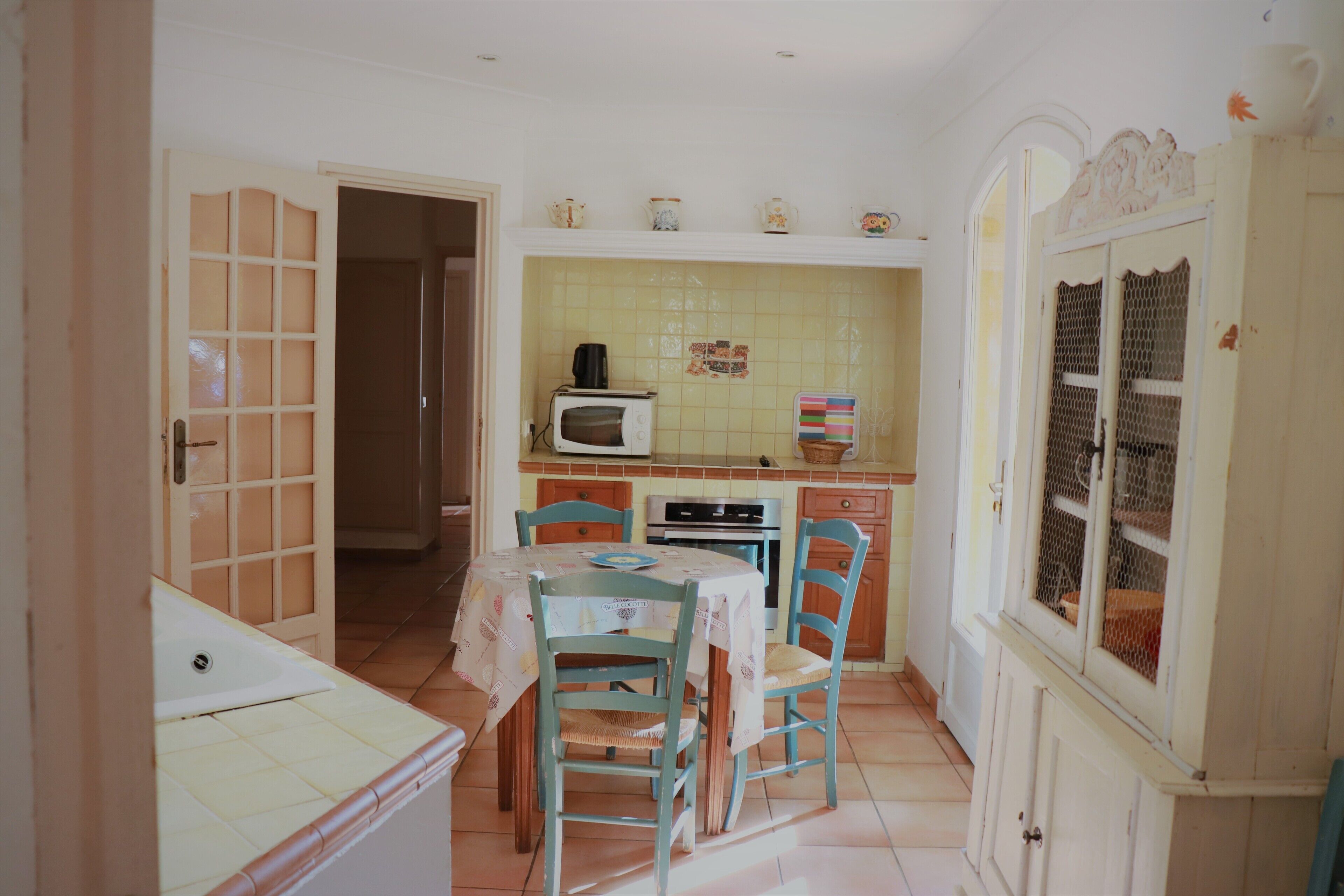 Une petite cuisine équipée d’une table à manger, de chaises, d’un four à micro-ondes et d’une cuisinière.