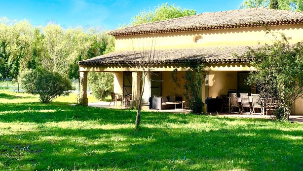 A traditional building with a tiled roof and a covered patio area. - Single storey villa, 4 bedrooms, swimming pool, near the beaches of the Gulf of Saint Trop (Grimaud)