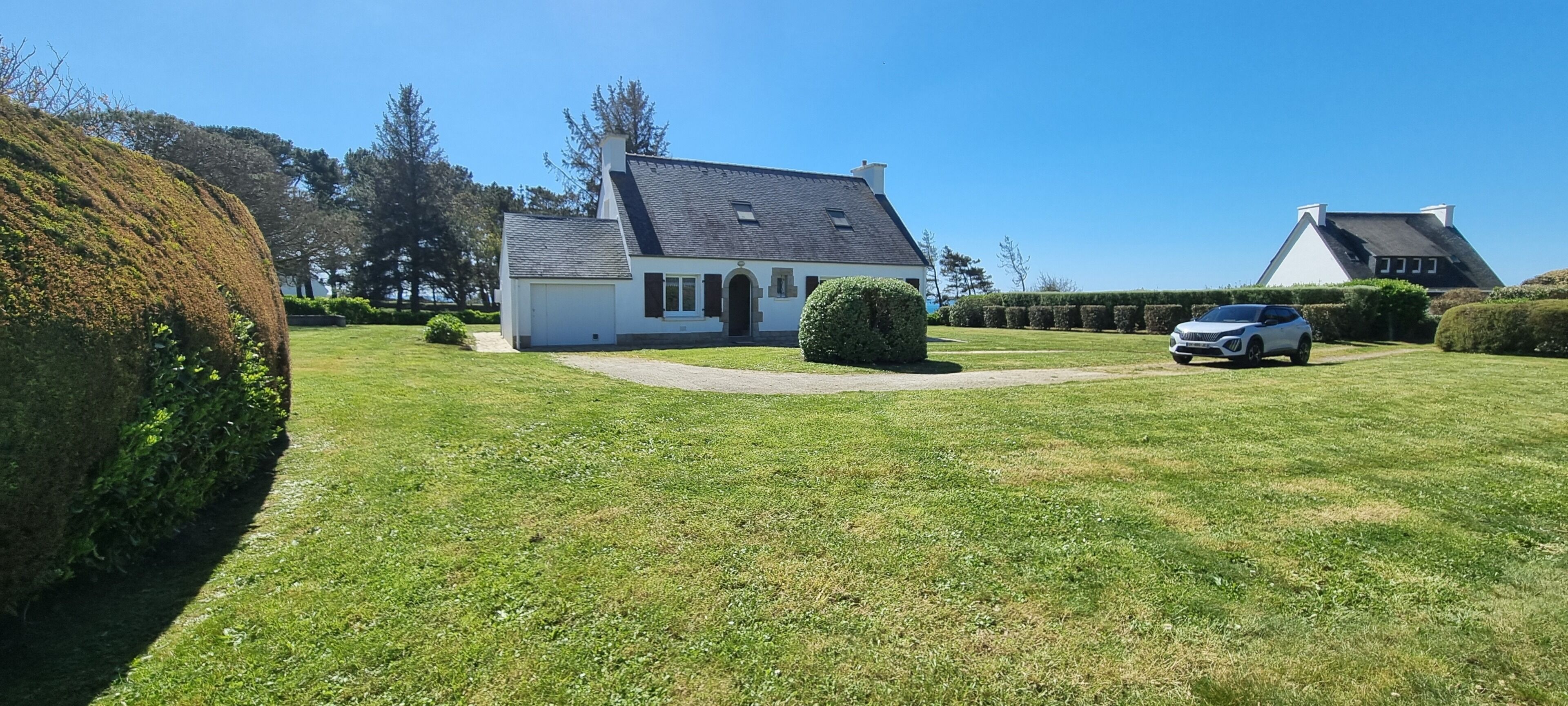 A house with a well-maintained lawn, a driveway, and a parked car.