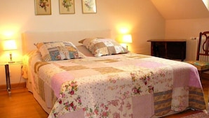 Un dormitorio con una cama grande, dos lámparas de noche y tres cuadros con motivos florales en la pared.