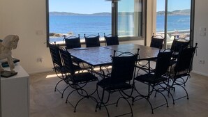 A spacious dining area with a large table and chairs, large windows offering a view of the sea, and a rustic ceiling. - St Tropez Gulf, luxury villa, very close to the sea with Jaccuzi Ste Maxime (Sainte-Maxime)