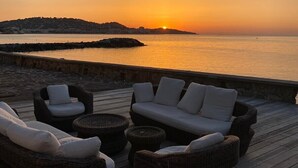 A sunset view from a wooden deck with wicker furniture and a stone wall. - St Tropez Gulf, luxury villa, very close to the sea with Jaccuzi Ste Maxime (Sainte-Maxime)