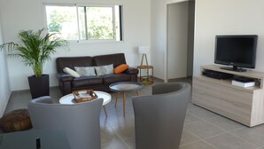 A modern living room with a sofa, coffee table, and armchairs. There is a television, a plant, and a small side table. - Carnac - Close to beaches and shops - 3 bedrooms (Carnac)