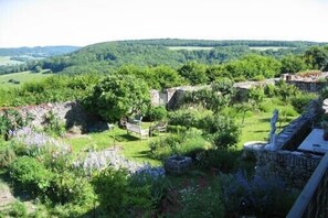 A garden with stone walls, a bench, and a statue.