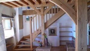 A rustic interior with a wooden staircase, a small table with a vase, and a bench. - A quiet and comfortable house in a burgundy's medieval village (Flavigny-Sur-Ozerain)