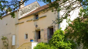 A traditional stone house with a sloped roof, a small porch, and a window with shutters. - A quiet and comfortable house in a burgundy's medieval village (Flavigny-Sur-Ozerain)