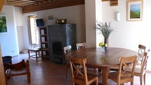 A dining area with a round table and wooden chairs, a fireplace, and a window with a view. - A quiet and comfortable house in a burgundy's medieval village (Flavigny-Sur-Ozerain)