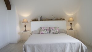 A bedroom with a bed, two bedside tables with lamps, a nightstand, and a shelf with decorative items. - CHARMING, BRIGHT 8-PERSON HOUSE CLOSE TO THE BEACH AND SUSCINIO CASTLE (Sarzeau)