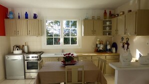 A kitchen with a dining table, chairs, a stove, an oven, and cabinets. - CHARMING, BRIGHT 8-PERSON HOUSE CLOSE TO THE BEACH AND SUSCINIO CASTLE (Sarzeau)