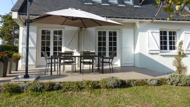 A house with a covered patio area featuring a table and chairs, a large umbrella, and a garden in the foreground. - CHARMING, BRIGHT 8-PERSON HOUSE CLOSE TO THE BEACH AND SUSCINIO CASTLE (Sarzeau)