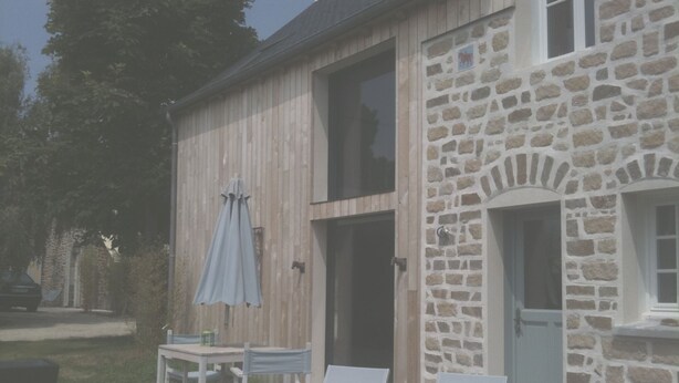A stone building with a wooden deck, a table with chairs, and two lounge chairs. - Villa with sea view and terrace, very sunny south-west exposure (Saint-Suliac)