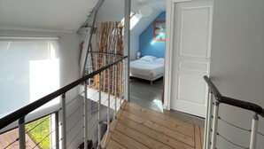 A wooden staircase leading to a bedroom with a bed and a nightstand. - Villa with sea view and terrace, very sunny south-west exposure (Saint-Suliac)