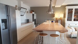 Une cuisine moderne dotée d’un îlot central, de tabourets de bar, d’un réfrigérateur et d’un luminaire suspendu.