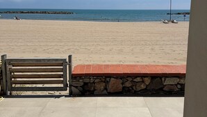 Une plage avec un banc et un muret en pierre.