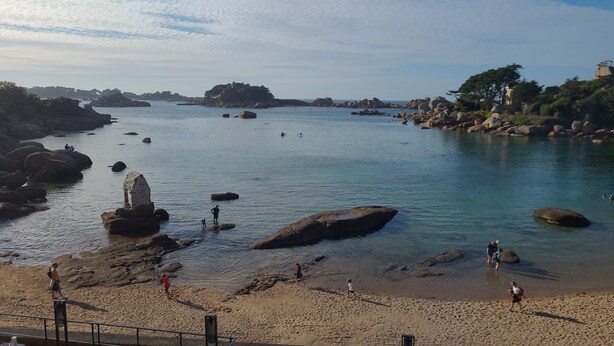 A coastal beach with clear water, large rocks, and people walking along the shore. - Prepare your future vacations... all in Roz! (Perros-Guirec)