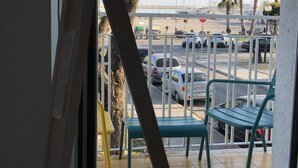 A balcony with a view of a parking area, including cars and palm trees.