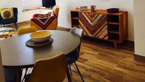 A modern dining area with a round table, chairs, and a decorative wall piece.