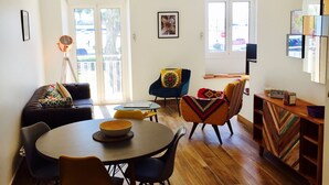 A modern living room with a dining area, featuring a sofa, chairs, a table, and a wooden cabinet.