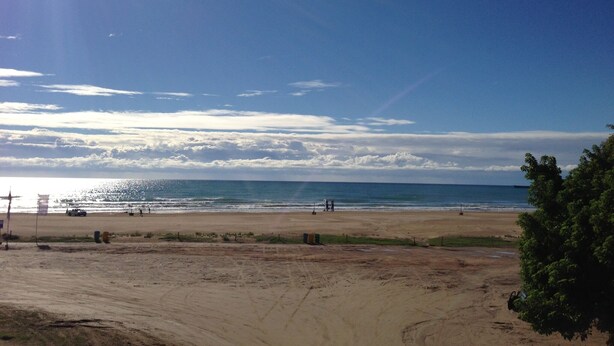 A beach with a clear sky, sandy shore, and a few people.
