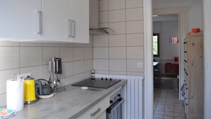 Ett kompakt kök med vita skåp, en inbyggd spis och en liten arbetsbänk.