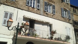Un immeuble à plusieurs étages, doté de balcons, de grandes portes en bois et d’un lampadaire.