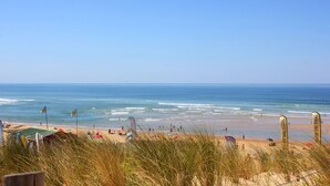 Ein Strand mit Flaggen, Sonnenschirmen und Menschen.
