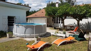 Ein Garten mit Schwimmbad, Liegestühlen und einem kleinen Tisch.