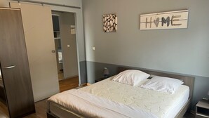 A bedroom with a bed, a wardrobe, a nightstand, and a wall-mounted sign.