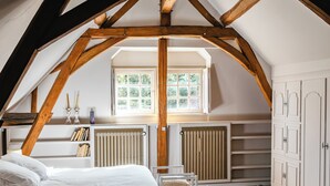 A bedroom with a sloped ceiling, wooden beams, a bed, a chair, a radiator, and a window. - Luxury property with pool in Tourraine (Saché)