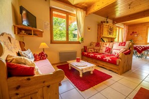 A cozy wooden-furnished living room with a sofa, a table, and a TV.