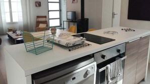 A modern kitchen with a central island, built-in oven, and a black stove. - House with courtyard, 200 m from the Remblai and 3 minutes from Les Sables town center on foot! (Les Sables-D'olonne)