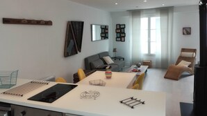 A modern living room with a sofa, a dining table, and a kitchen area with a stove and drying rack. - House with courtyard, 200 m from the Remblai and 3 minutes from Les Sables town center on foot! (Les Sables-D'olonne)