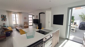 A modern kitchen with a built-in stove, a dining area with a white table and chairs, and a living room with a sofa and a chair. - House with courtyard, 200 m from the Remblai and 3 minutes from Les Sables town center on foot! (Les Sables-D'olonne)