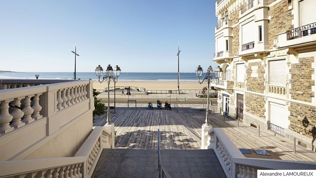 A coastal promenade with a view of the beach, a staircase leading to a building, and street lamps. - House with courtyard, 200 m from the Remblai and 3 minutes from Les Sables town center on foot! (Les Sables-D'olonne)