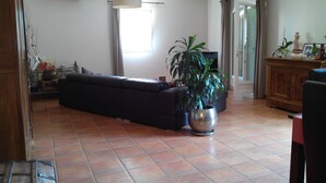 A living room with a sofa, a potted plant, and a television. - Beautiful Villa (Bastide) close to the sea and Pic Saint Loup (Sussargues)