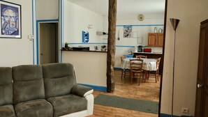 Una sala de estar con sofá, un comedor con mesa y sillas, y una cocina con armarios y encimera.