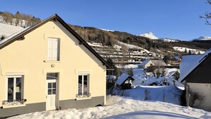 Un pueblo cubierto de nieve con casas tradicionales, una montaña al fondo y un cielo despejado.