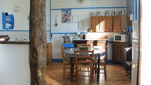 Una cocina con armarios de madera, una mesa redonda con sillas, un microondas y un refrigerador.