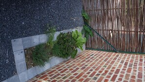 Eine Pflasterterrasse mit Betonrand und einer Bambusumzäunung.