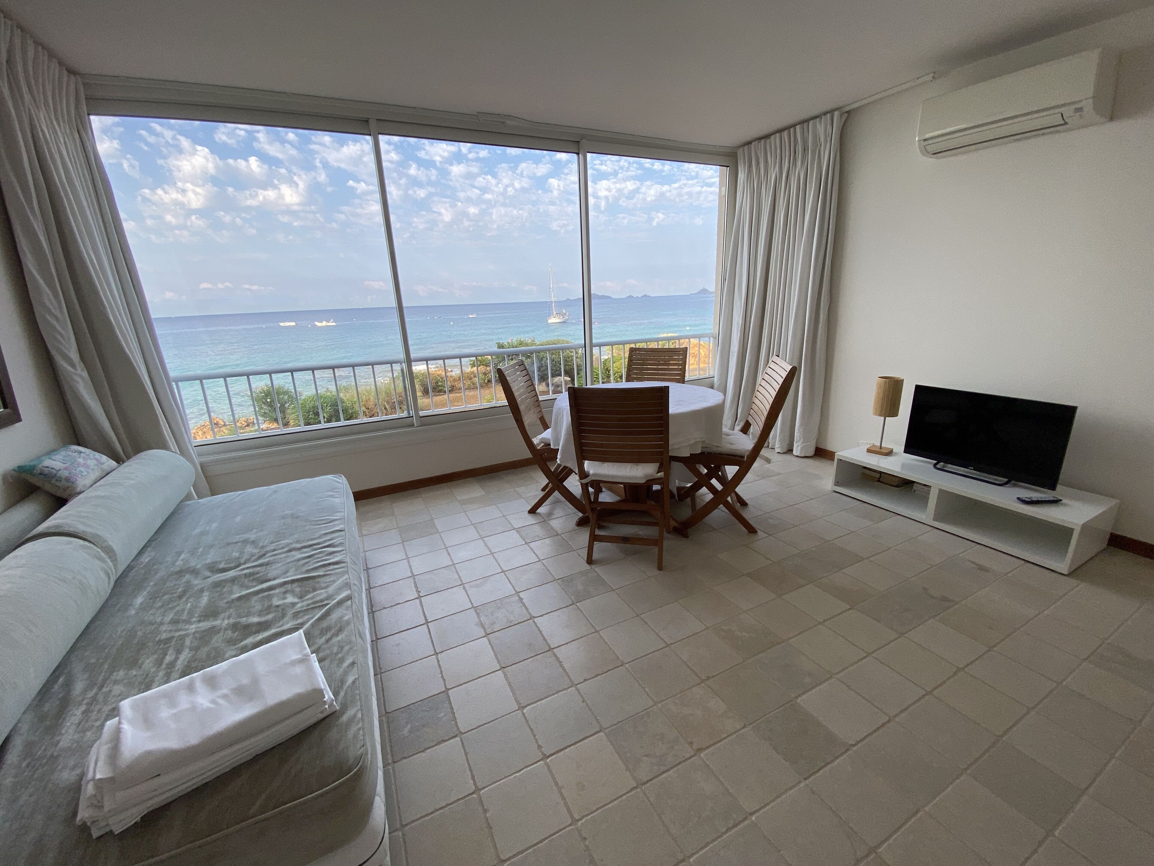 Une chambre d’hôtel avec un balcon, une télévision, une table à manger avec des chaises et un lit.