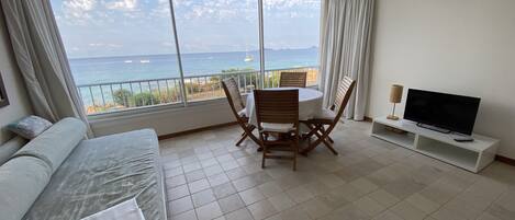 Une chambre d’hôtel avec un balcon, une télévision, une table à manger avec des chaises et un lit.