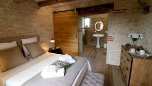 Un dormitorio con una cama de madera, un aparador y una pared de piedra.