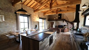 Una cocina amplia con una isla grande, piso de madera y una pared de piedra rústica.
