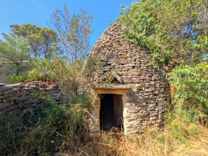 A stone hut with a small entrance, surrounded by vegetation. - In Uzès, 93m² airco+private terrace, sw.-pool 9X9, WIFI, huge garden, very quiet (Uzès)