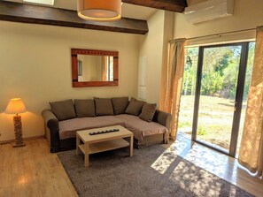 A living room with a sectional sofa, a coffee table, a lamp, and a large mirror. - In Uzès, 93m² airco+private terrace, sw.-pool 9X9, WIFI, huge garden, very quiet (Uzès)