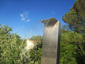 A metallic sculpture with water flowing from its top, surrounded by greenery and a clear blue sky. - In Uzès, 93m² airco+private terrace, sw.-pool 9X9, WIFI, huge garden, very quiet (Uzès)