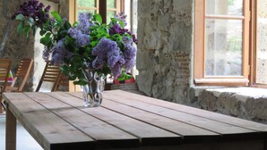 Une table en bois rustique sur laquelle est posé un vase en verre transparent contenant des fleurs violettes.