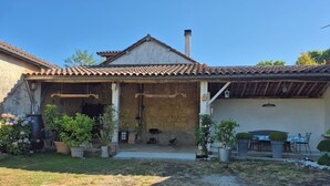 A rustic house with a tiled roof, a chimney, and a covered patio area with outdoor seating. - Children's paradise calm nights, guest animals, plenty of Playmobilss (Troncens)